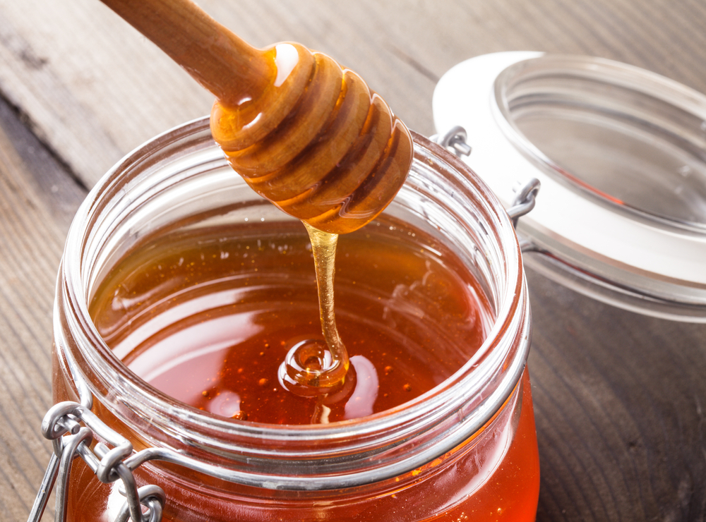 Photo showing open jar of honey